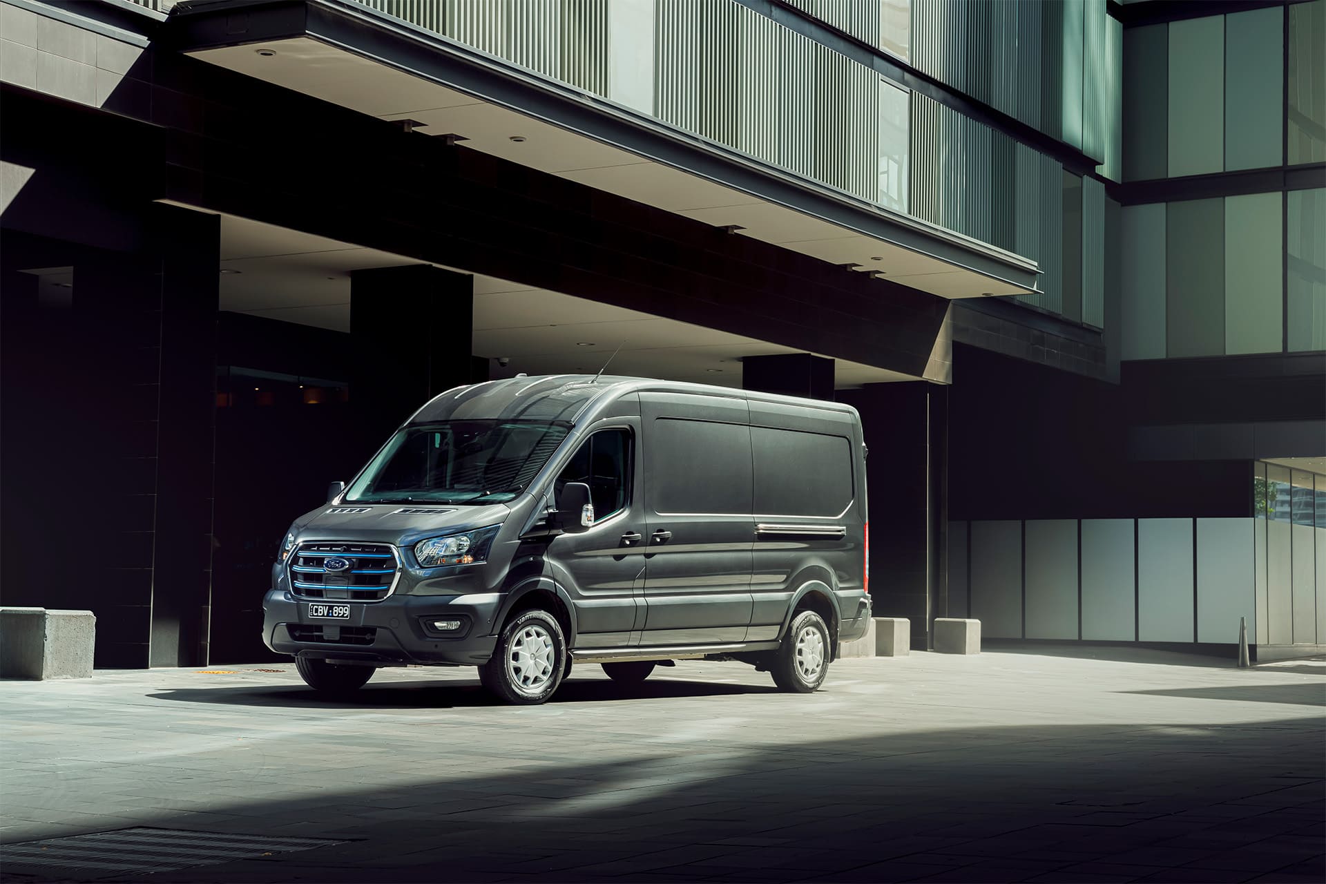 A 2019 Ford Transit van parked in front of a modern building on a sunny day.