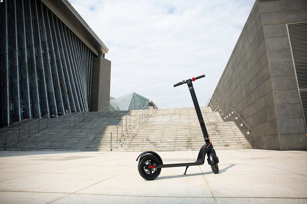 A black scooter parked on a smooth concrete floor, showcasing its sleek design and sturdy build.