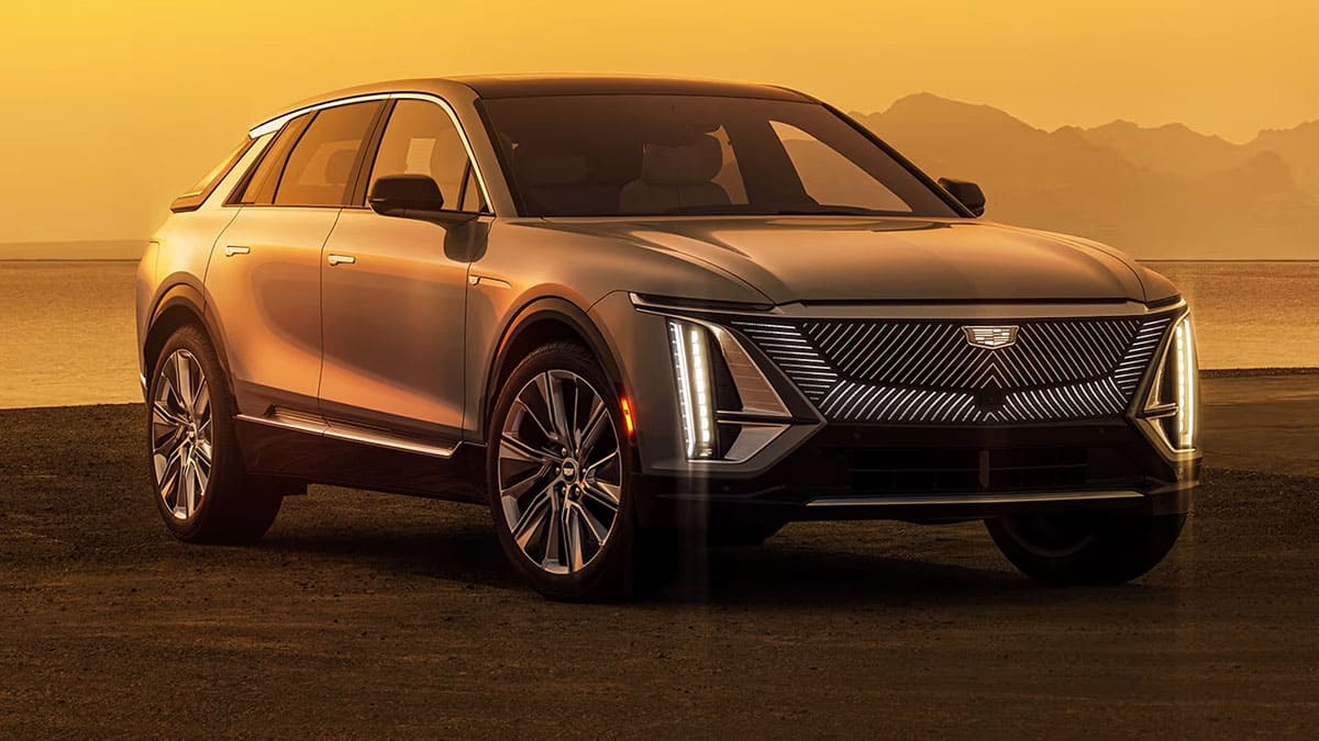 A Cadillac SUV parked in front of a majestic mountain landscape, showcasing its elegance against a natural backdrop.