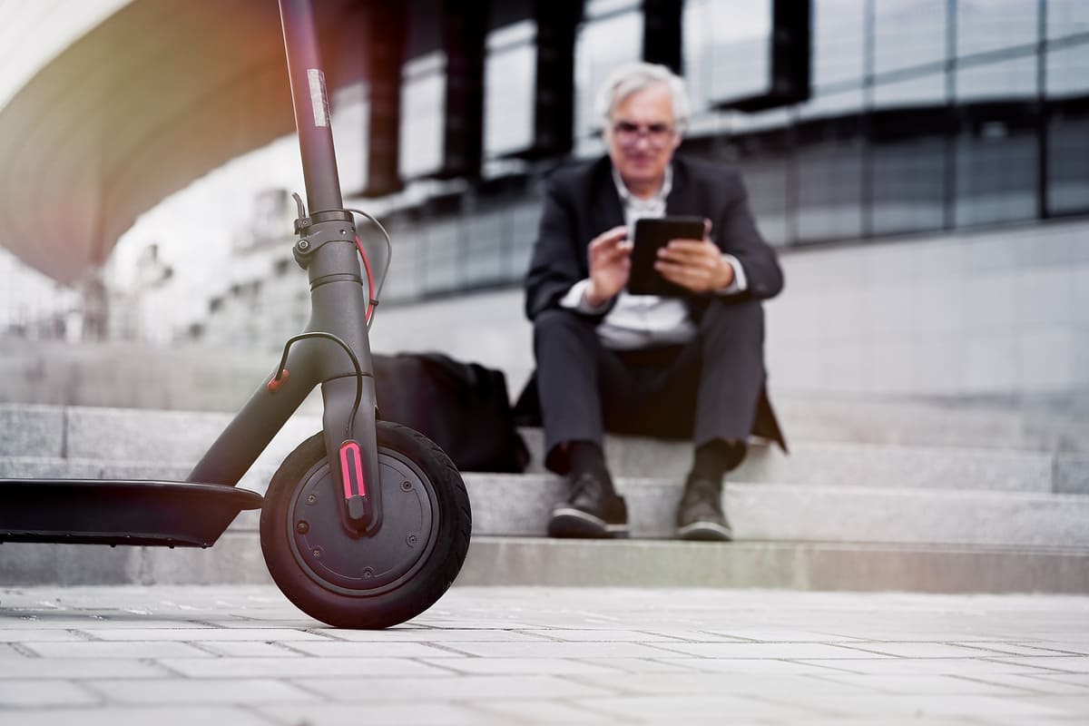 A man in a suit casually sits on a scooter, blending professionalism with a playful mode of transportation. A man in a suit casually sits on a scooter, blending professionalism with a playful mode of transportation.