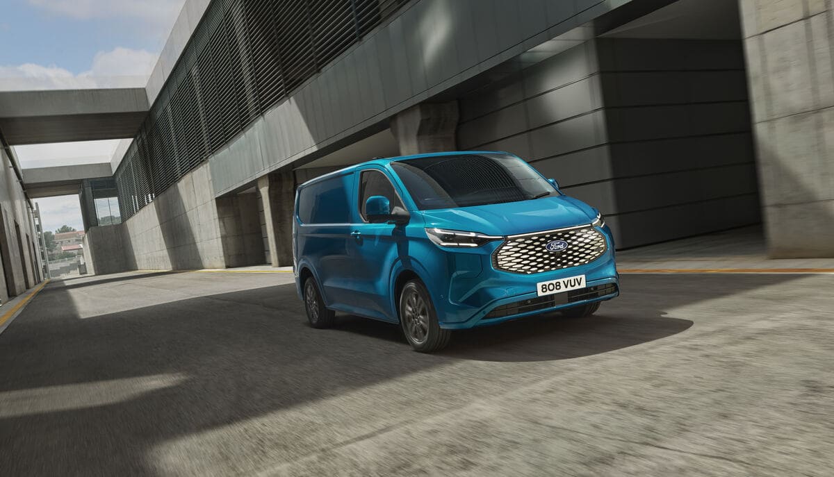 A new Ford electric van drives along a city street, showcasing its modern design and eco-friendly technology.