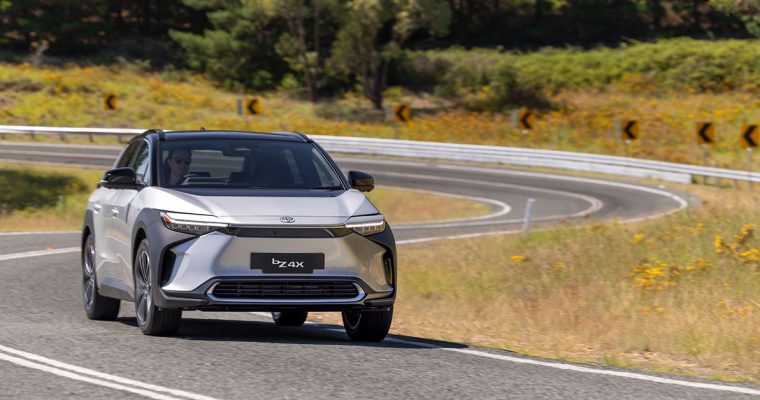 A new Toyota Mirai drives along a scenic road, showcasing its sleek design and advanced technology.