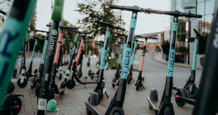 A row of electric scooters parked neatly along the sidewalk, ready for use. A row of electric scooters parked neatly along the sidewalk, ready for use.