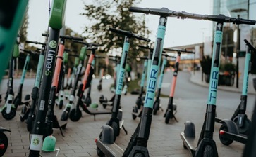A row of electric scooters parked neatly along the sidewalk, ready for use. globalblog'