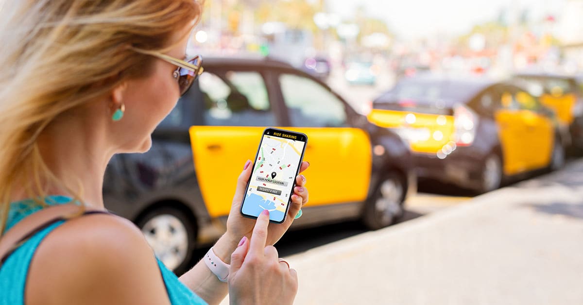 A woman checks a taxi app on her cell phone while standing on a city street. A woman checks a taxi app on her cell phone while standing on a city street.