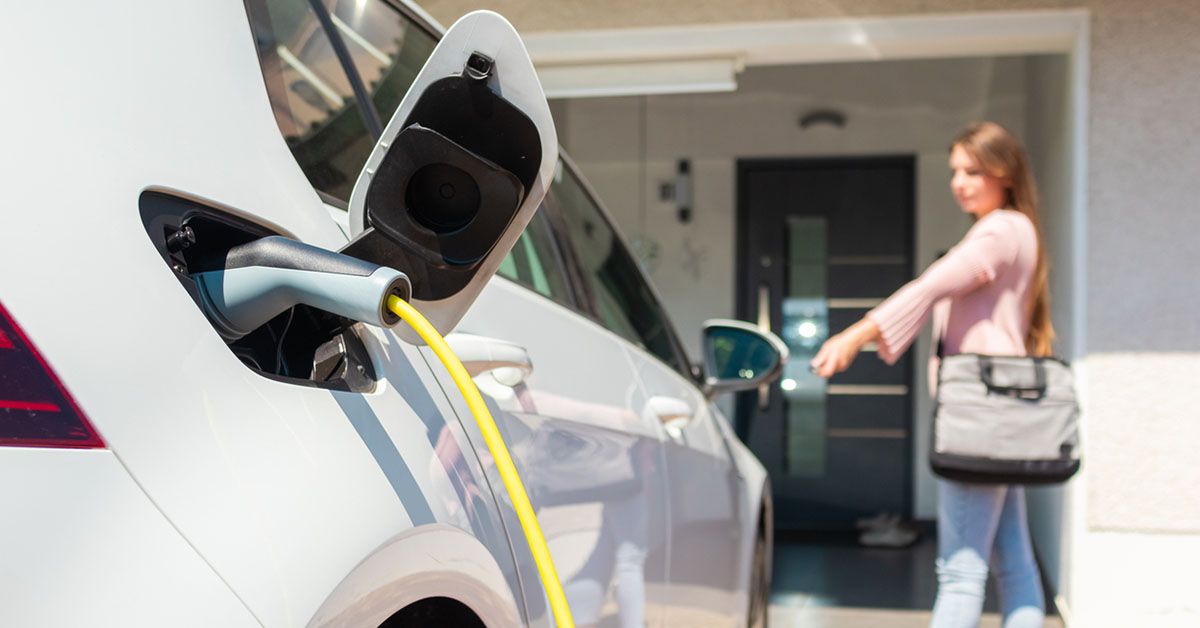 A woman is charging her electric car at a charging station, showcasing sustainable energy use and modern technology.
