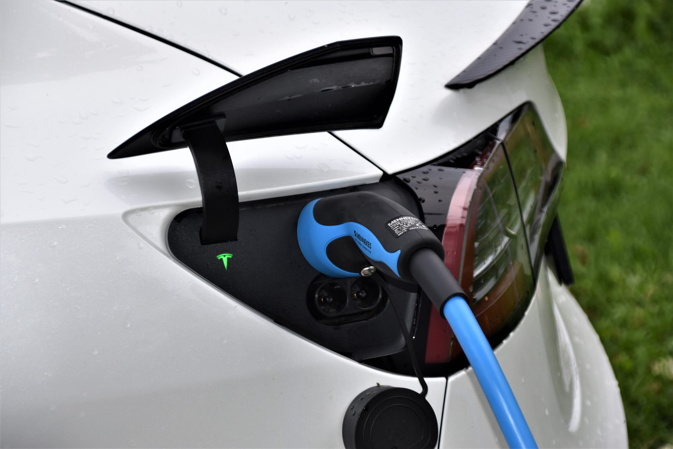 An electric car charging at a station, plugged into an electric charger for power. An electric car charging at a station, plugged into an electric charger for power.
