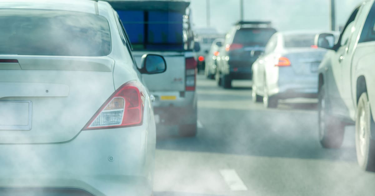 Cars navigating a highway, emitting smoke from their exhausts, illustrating urban traffic and environmental impact.
