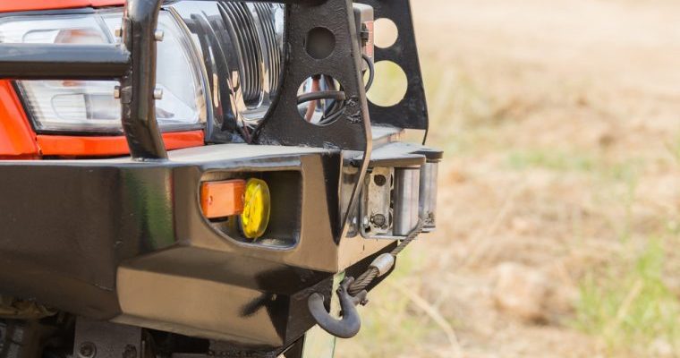 Close-up view of a red Jeep's front bumper, showcasing its rugged design and vibrant color.