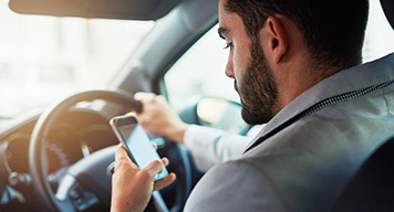 Man-driving-car-checking-phone-safety-concerns Man-driving-car-checking-phone-safety-concerns