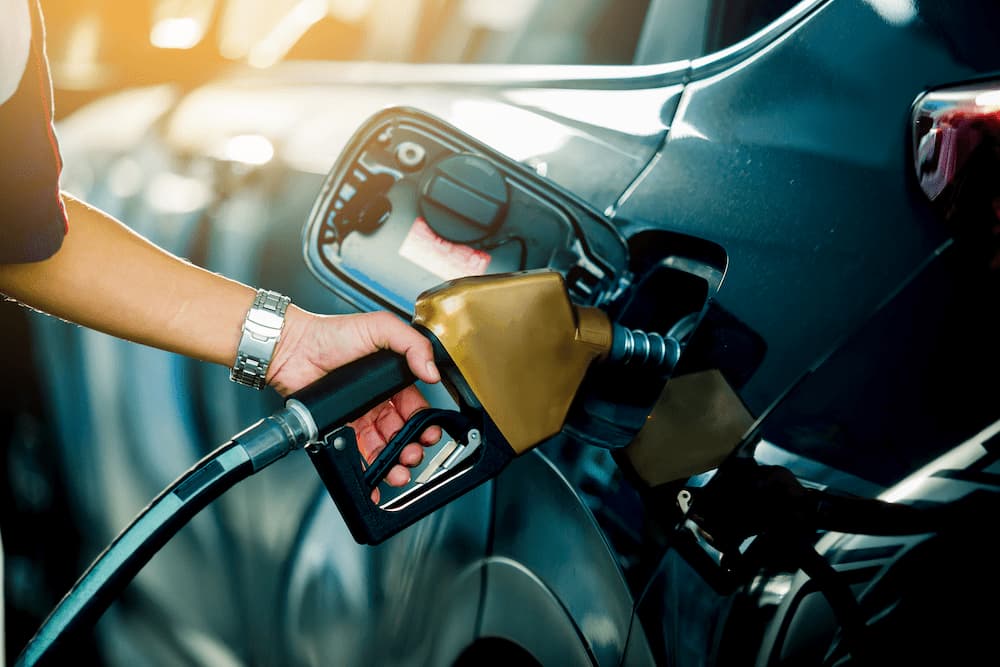 Close‑up of a person refuelling a car at a petrol station.