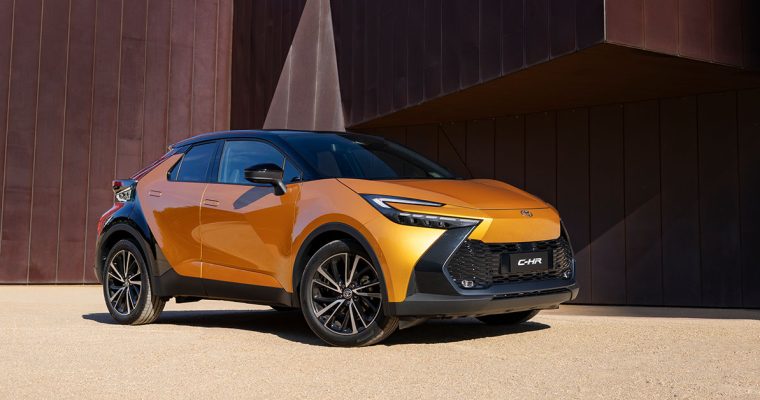 Toyota C-HR SUV parked in front of a modern building, showcasing its sleek design and urban appeal.
