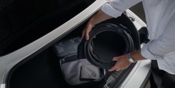 Man removing a Type 2-Type 2 cable from the car boot.