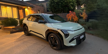 Kia EV3 in Matcha Green parked in the driveway of a leafy suburban home.