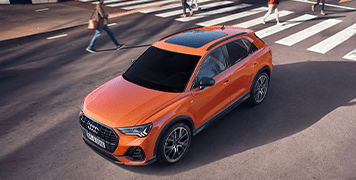 Street scene of Audi Q3 small SUV with orange paint at a crossing