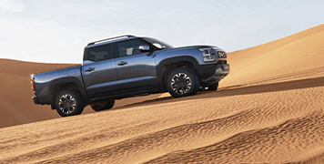 BYD SHARK 6 ute in blue ascending a sand dune.