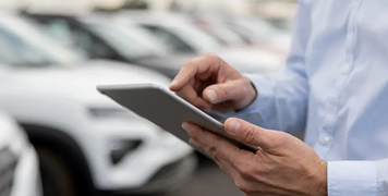 Close-up-on-a-man-using-a-tablet-computer-at-the-car-dealership
