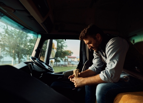 A fatigued driver looks downcast in his cab