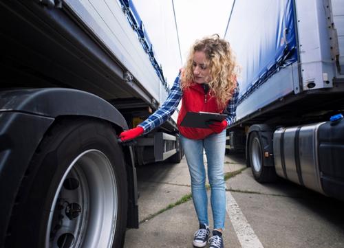a female driver checks her lorry before setting off