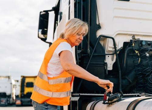 A female truck driver in a hi-vis carries out lorry checks