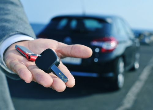 A hand offers a key to a company car