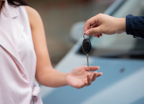 A woman receiving keys for a used car