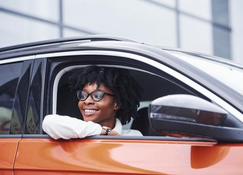 A woman smiling out of the window of her orange salary sacrifice scheme car