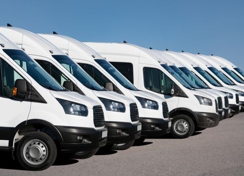 a fleet of white vans lined up at a depot