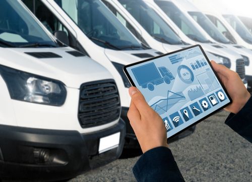 someone uses a tablet to manage a fleet of vans in a depot