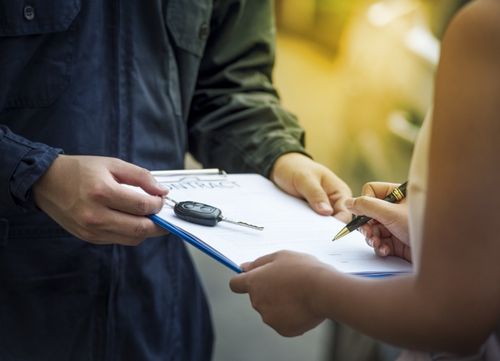 A person in overalls hands a customer a contract