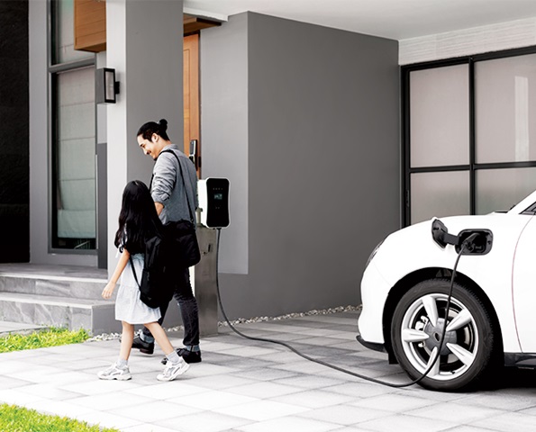 Man and girl walking into house with EV plugged into a home charger