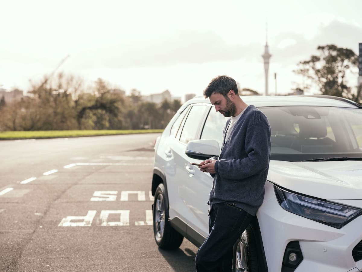 Person using a smartphone beside a parked SUV Person using a smartphone beside a parked SUV