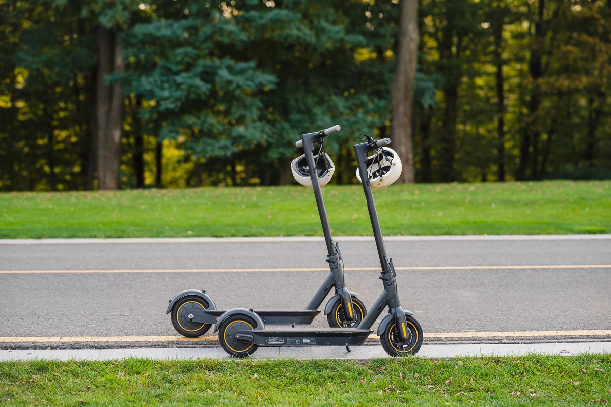 fully-defining-shared-mobility Two scooters with helmets on the footpath