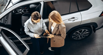 two women standing next to car