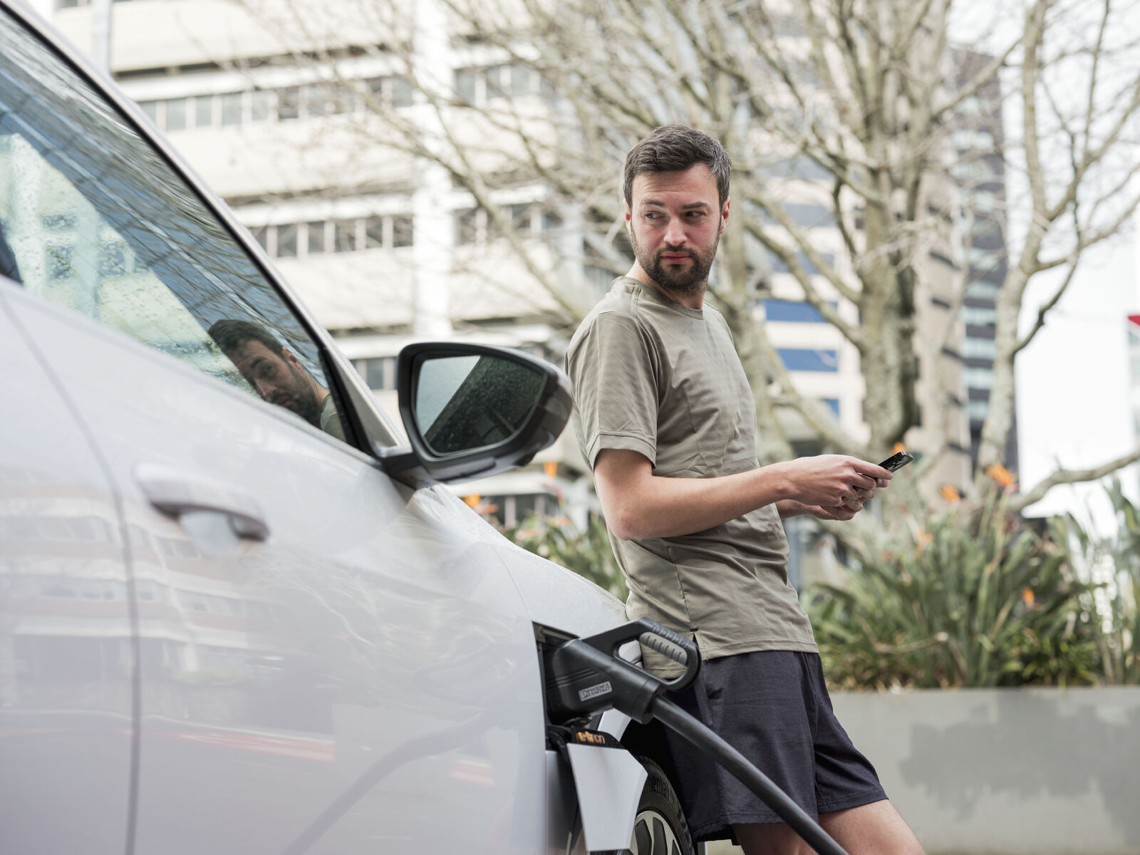SGFleet_NZ_Man_EV_Charging_Sept24-medium Man waiting for EV to charge at charging station in Auckland