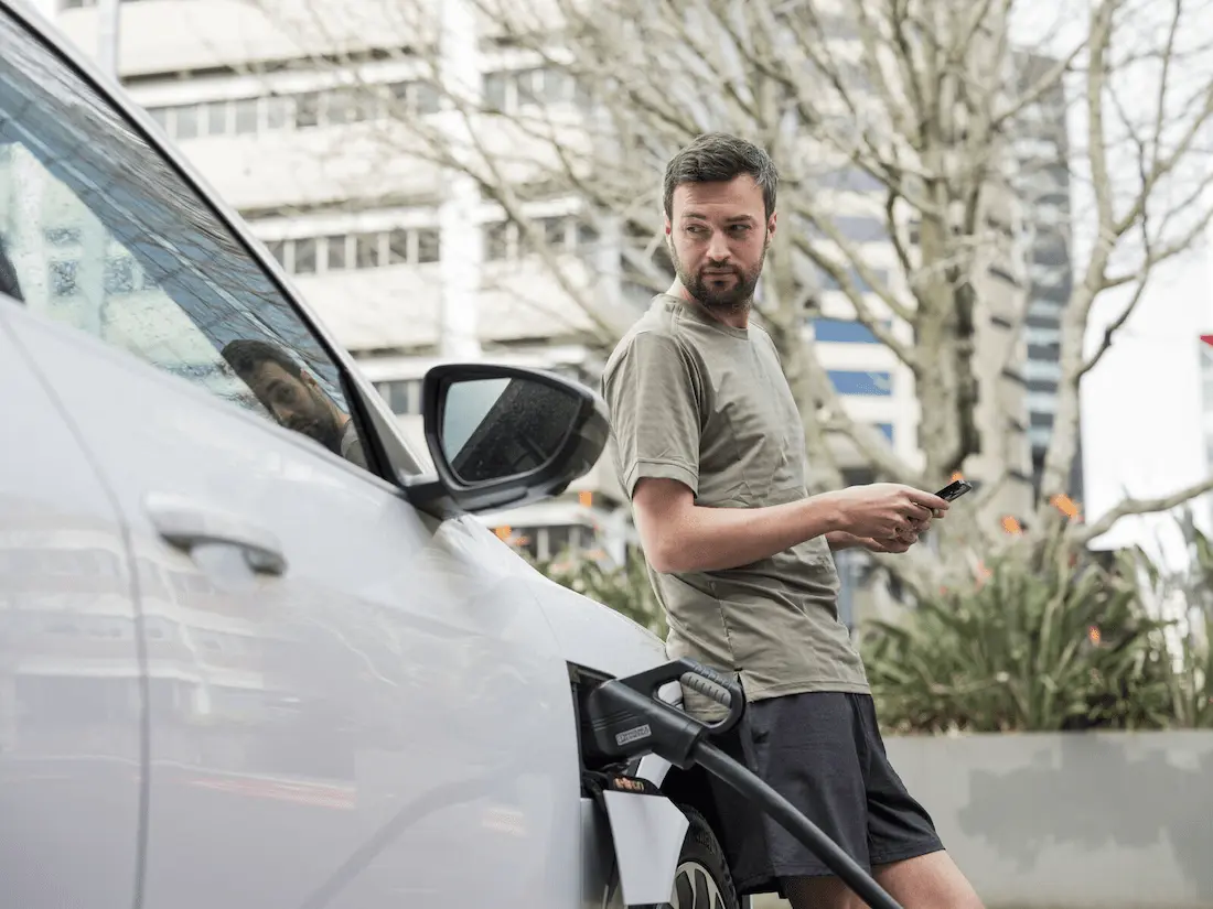 Man waiting for EV to charge at charging station in Auckland