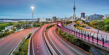 Auckland city with the Skytower in the background and state highway one and bike lane in the foreground