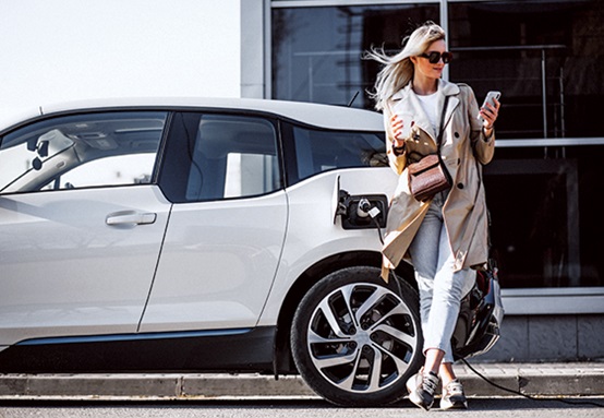Women leaning on EV whilst charging
