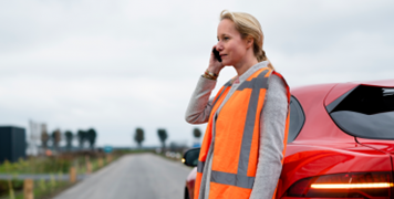 Woman on her phone leaning on the vehicle
