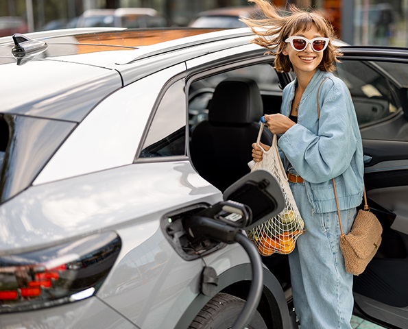 woman-putting-groceries-in-car-backseat-at-charging-station