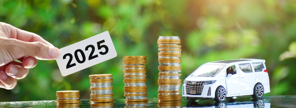 Stacks of coins beside a toy car with a hand holding a 2025 sign, symbolising how the 2025 Budget could influence motoring costs and vehicle expenses.