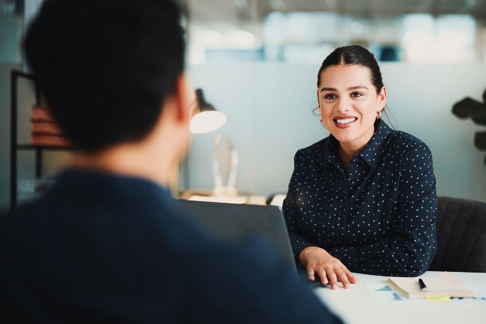 best places to work SG Fleet best places to work SG Fleet: A smiling woman in a navy polka-dot blouse sits across a desk from a colleague in a bright, modern office.