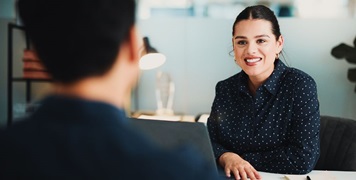 best places to work SG Fleet: A smiling woman in a navy polka-dot blouse sits across a desk from a colleague in a bright, modern office.