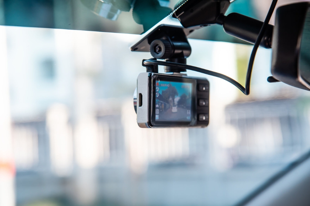 In-car dashcam mounted behind the rearview mirror, actively recording the road ahead.