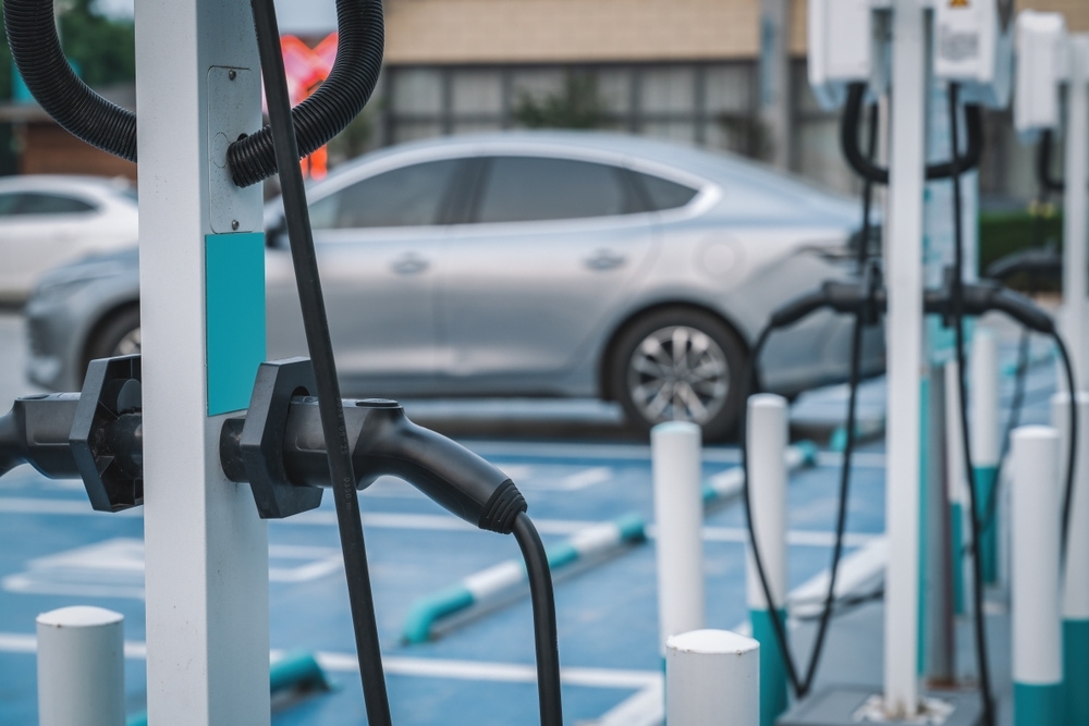 Business EV charging, a close-up view of an EV charge point with a silver electric fleet vehicle in the background, highlighting business EV charging setups